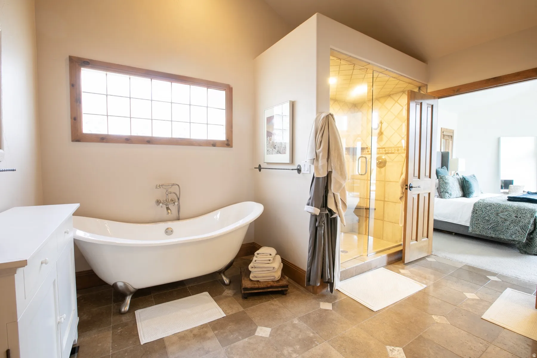 Bathroom featuring a freestanding soaking tub with polished chrome fixtures, a glass-enclosed shower with tiled walls, and patterned tile flooring
