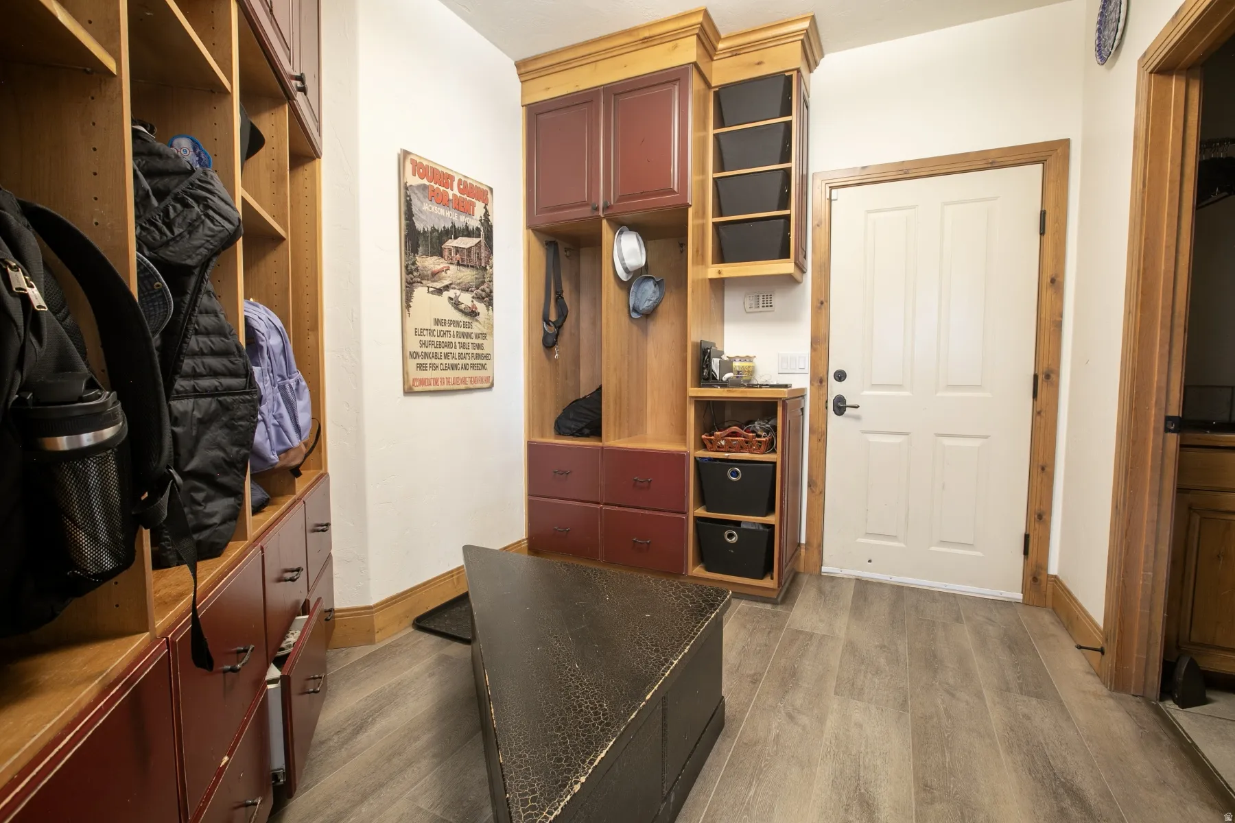 Entryway featuring built-in wood cabinetry with red-toned drawer and cabinet fronts, light wood-finish flooring, and a white paneled door with dark hardware