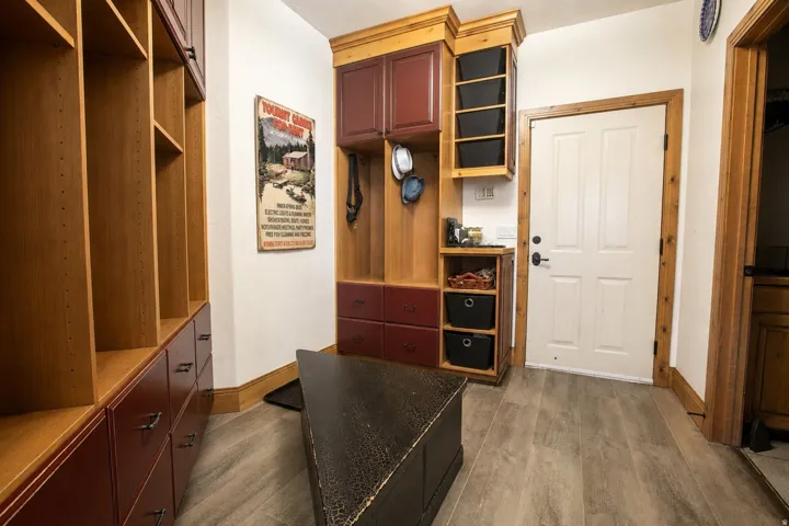 Entryway featuring built-in cabinetry with red and wood-finish accents, paneled door with wood trim, and wood-finish plank flooring