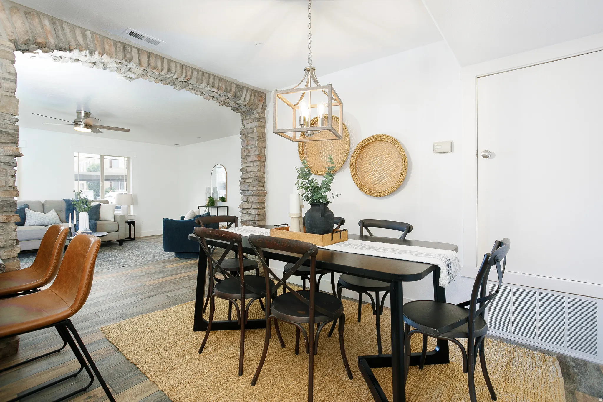 Open-concept dining area featuring wood-finish flooring, a contemporary chandelier, and a stone archway