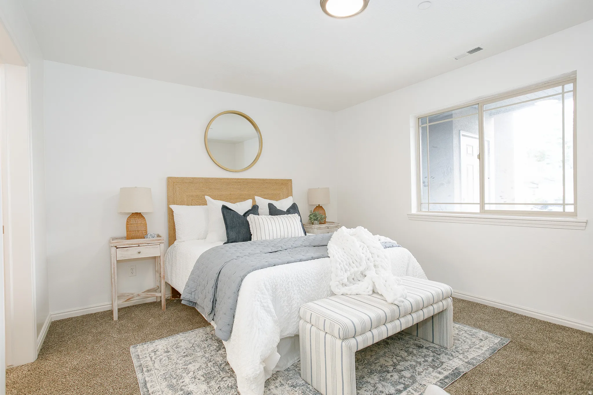 Light-filled room featuring a large window, neutral carpeting, and a flush-mount ceiling light