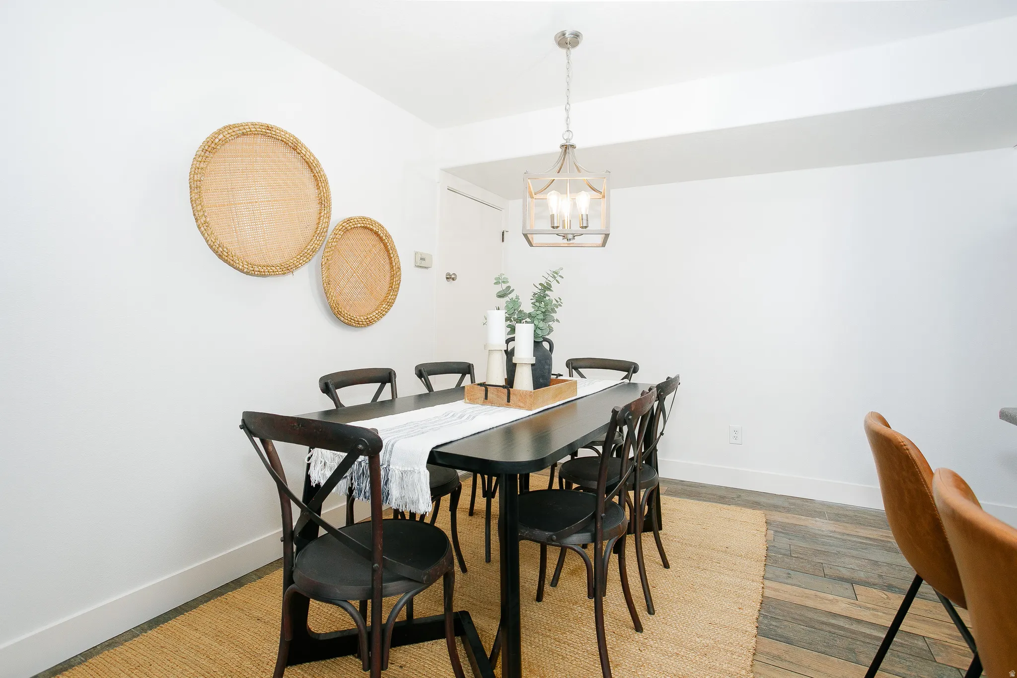 Dining area featuring white walls, a contemporary chandelier, and wood-finish flooring