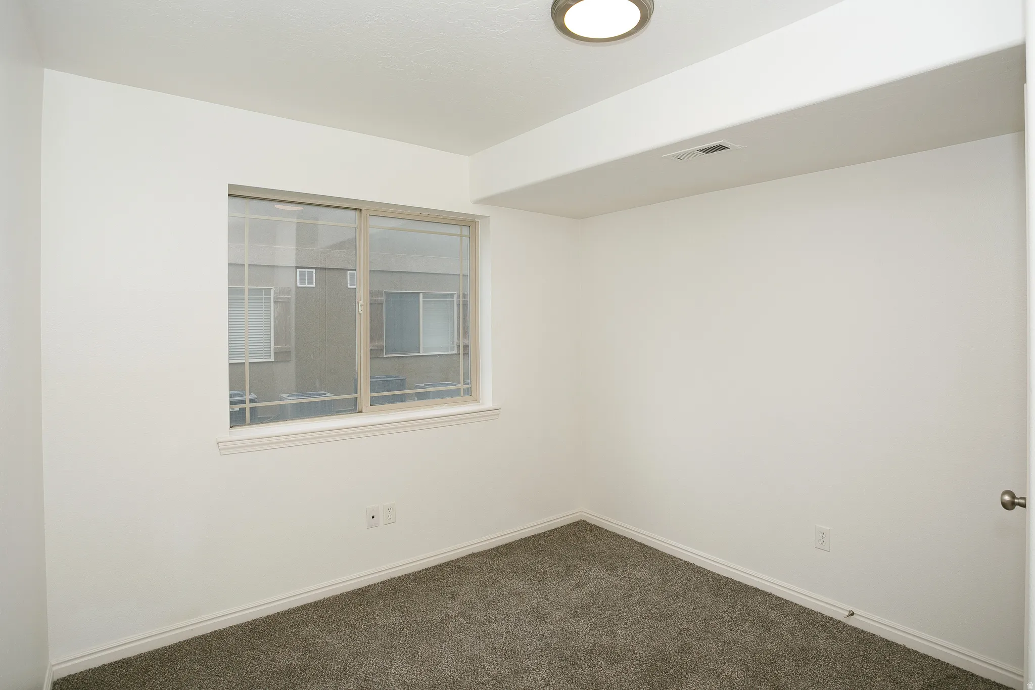 Room featuring a sliding window, white trim, light gray carpeting, and a flush-mount ceiling light