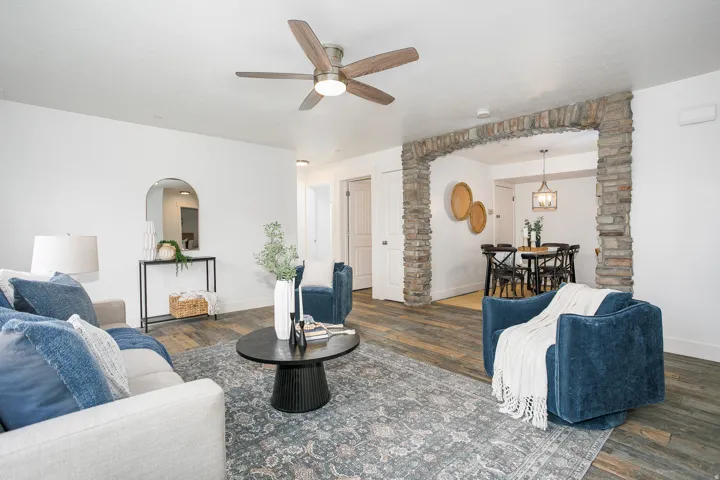 Spacious living area featuring wood-finish flooring, a ceiling fan, and a stone archway