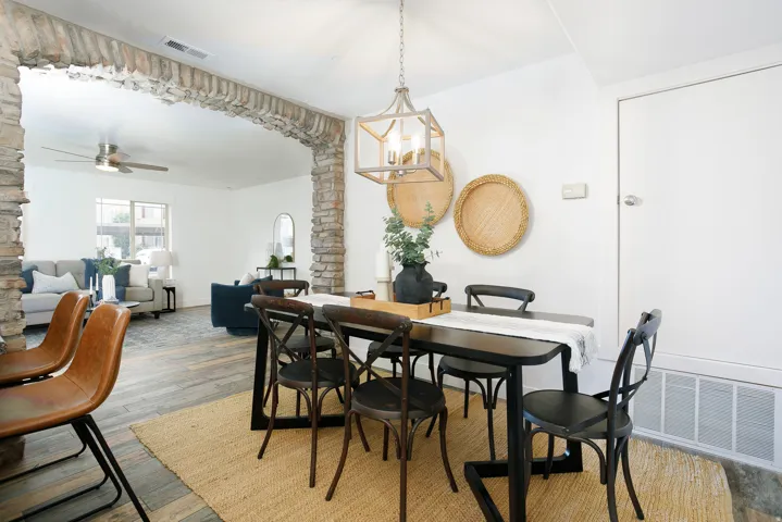 Open-concept dining area featuring wood-finish flooring, a contemporary chandelier, and a stone archway