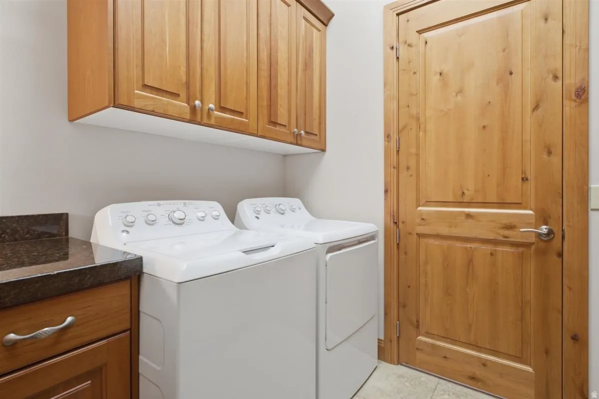 Laundry area featuring wood cabinetry, stone-finish countertop, and a solid wood paneled door with brushed nickel hardware
