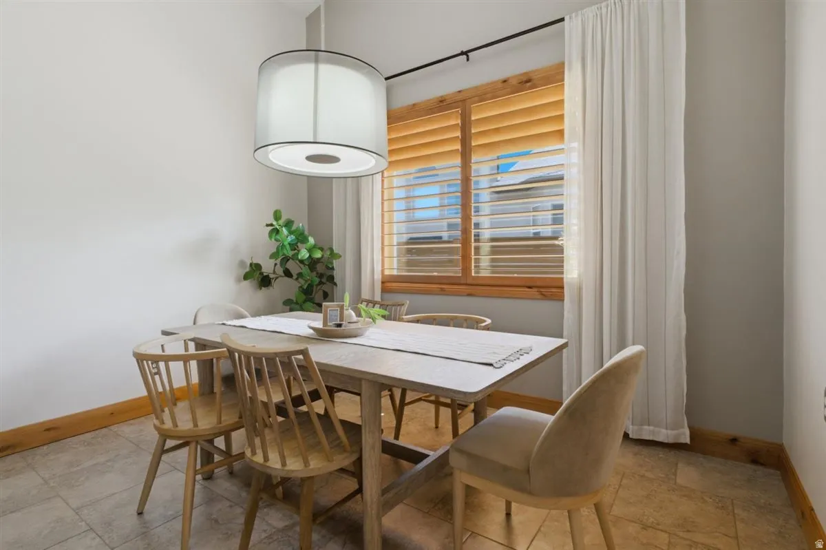 Dining area featuring a contemporary drum pendant light, wood-finish window blinds, and tile flooring