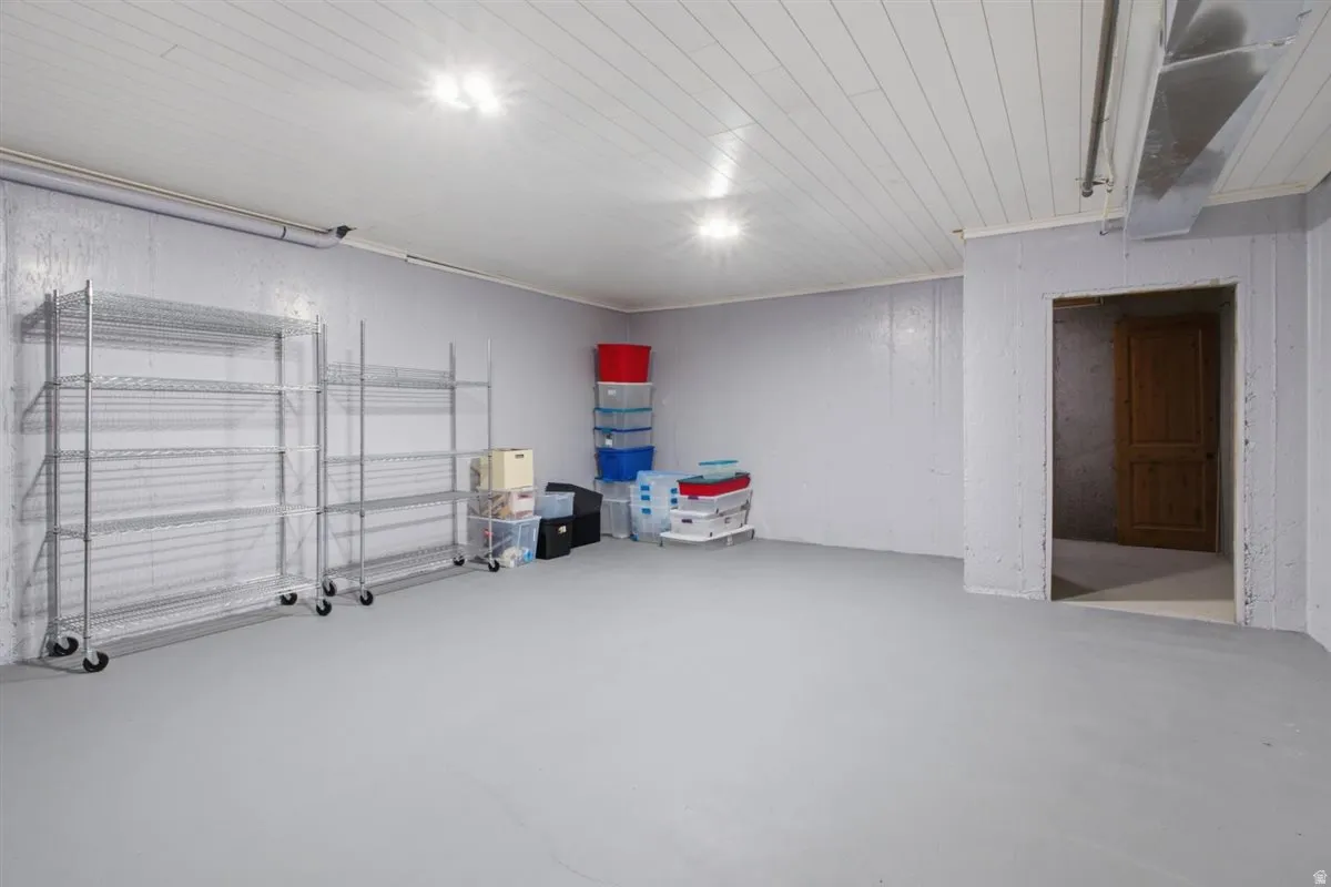 Utility room with painted concrete flooring and walls, illuminated by overhead lighting
