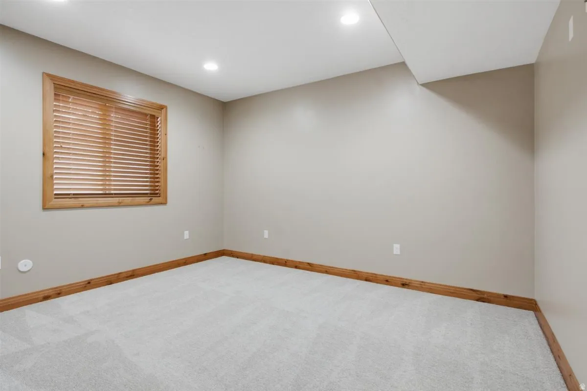 Carpeted room featuring a window with wood blinds and wood trim, recessed lighting, and neutral wall paint