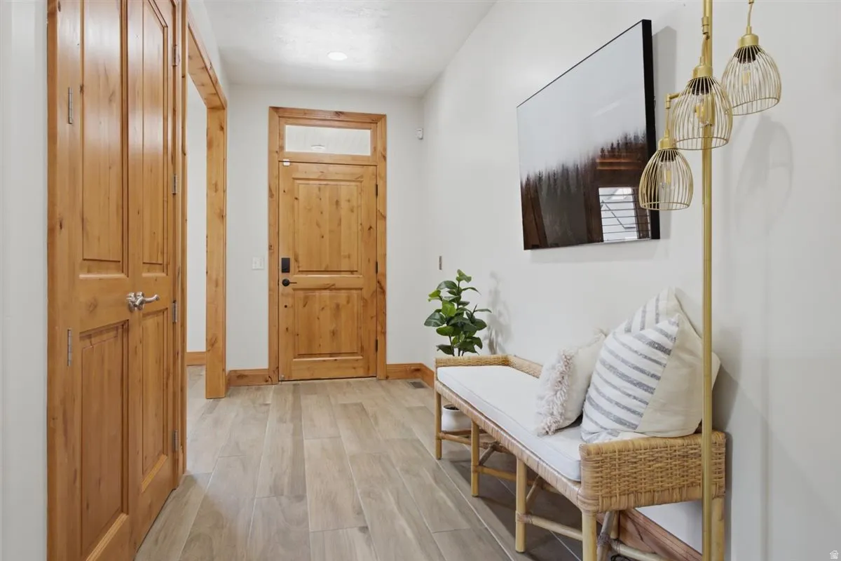 Entryway featuring a wood-finish door with transom window, light wood-finish flooring, and light-toned walls