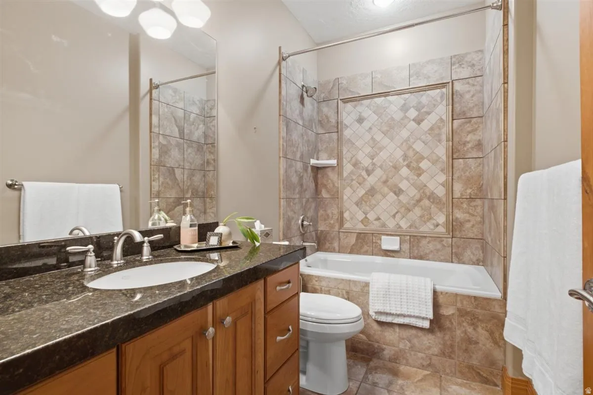 Bathroom featuring a single vanity with wood cabinetry, a dark countertop, and an undermount sink