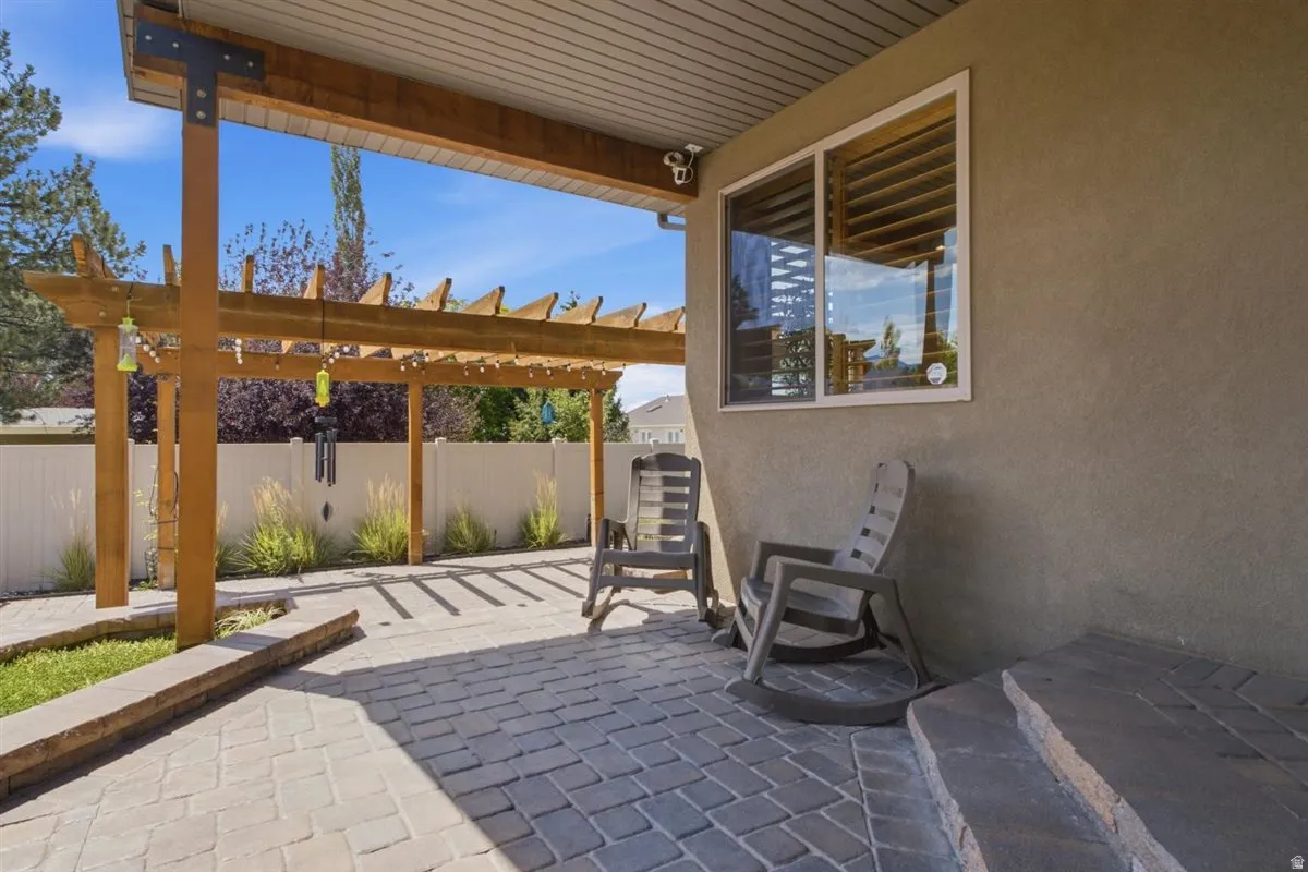 Stucco exterior featuring an attached pergola with wood beams