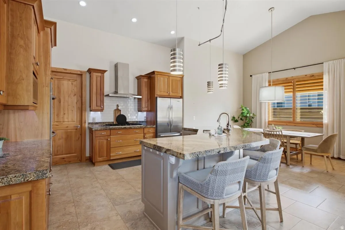 Gourmet kitchen featuring custom wood cabinetry, stainless steel appliances, and a large island with waterfall-edge countertop seating