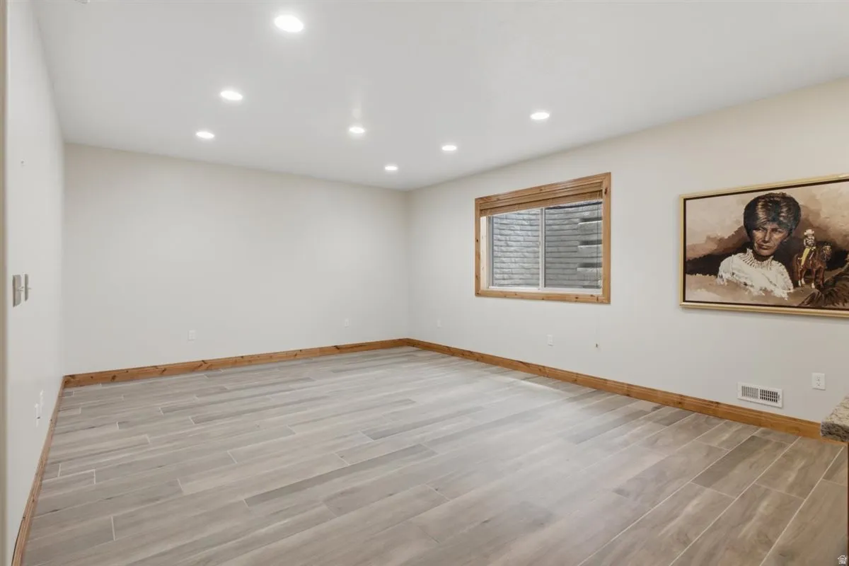 Spacious room featuring light-toned walls, wood-finish baseboards, and wood-finish window trim