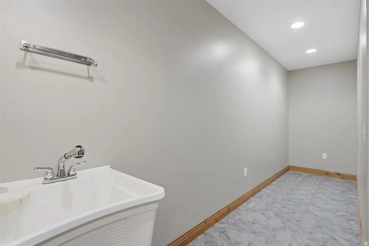 Utility sink with chrome faucet and pull-out sprayer, recessed lighting, and gray resilient flooring