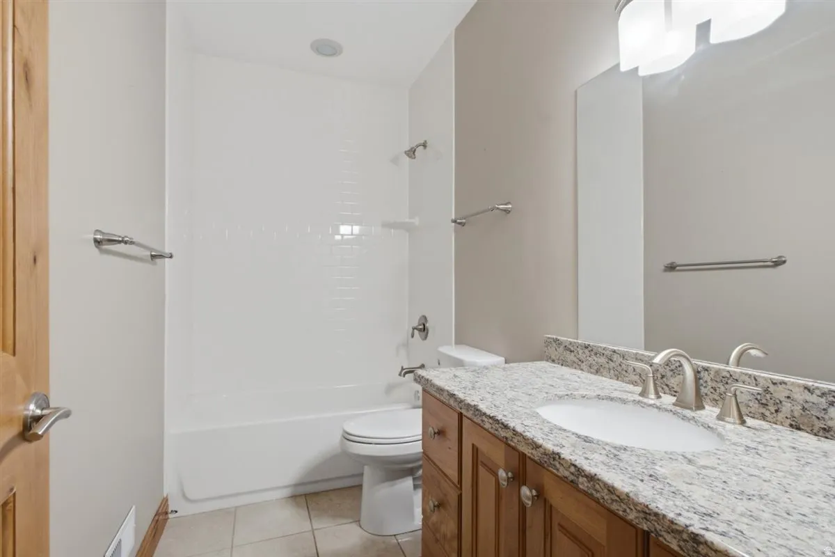 Bathroom featuring a wood vanity with a granite-style countertop, undermount sink, and brushed nickel fixtures