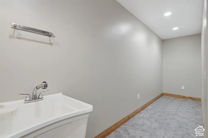 Utility sink with chrome faucet and pull-out sprayer, recessed lighting, and gray resilient flooring