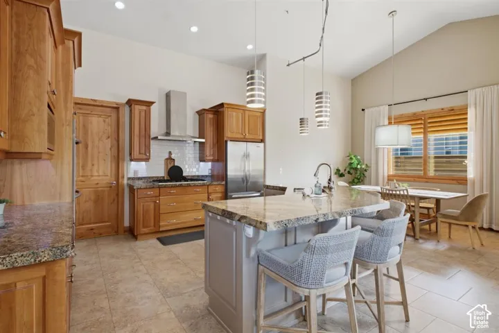 Gourmet kitchen featuring custom wood cabinetry, stainless steel appliances, and a large island with waterfall-edge countertop seating