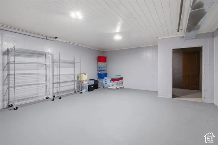 Utility room with painted concrete flooring and walls, illuminated by overhead lighting