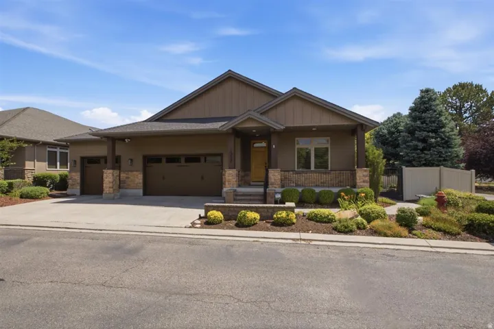 Contemporary ranch-style residence featuring a two-car garage, stone accents, and a covered front porch