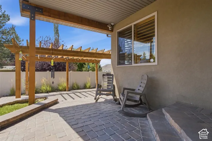 Stucco exterior featuring an attached pergola with wood beams