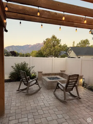 Outdoor paver patio with a built-in stone fire pit, surrounded by a low stone wall