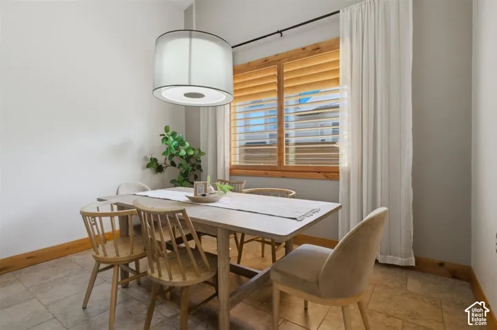 Dining area featuring a contemporary drum pendant light, wood-finish window blinds, and tile flooring