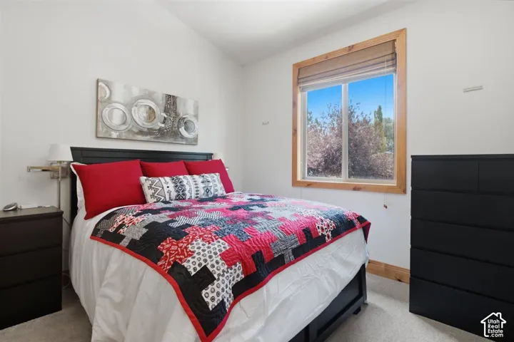 Bright upstairs room featuring a large window with natural wood trim, a vaulted ceiling, and carpet flooring