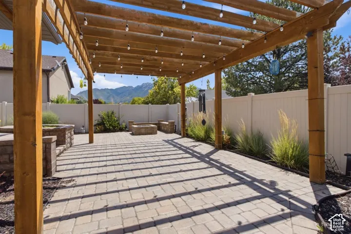 Expansive paver patio featuring a wooden pergola with string lighting