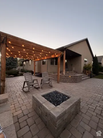 Paver patio featuring a built-in fire pit with dark stone fill