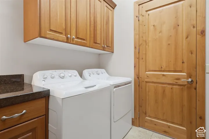 Laundry area featuring wood cabinetry, stone-finish countertop, and a solid wood paneled door with brushed nickel hardware