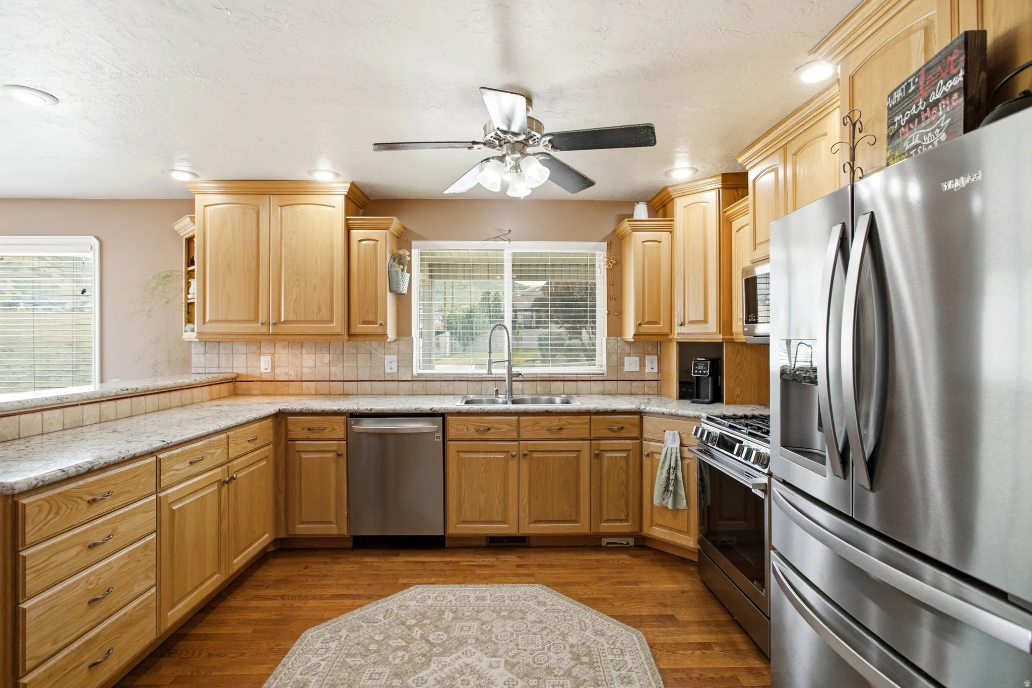 Kitchen featuring wood-finish cabinetry, stainless steel appliances, light-toned countertops, and a tile backsplash