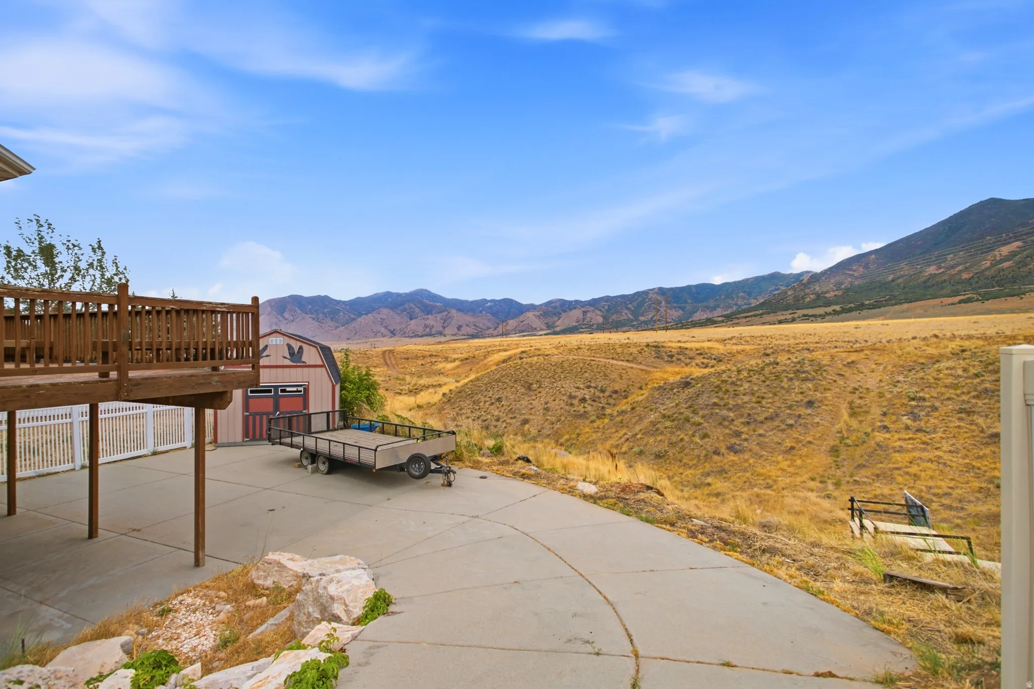 Expansive concrete patio with a wooden deck overhead, providing an outdoor living area