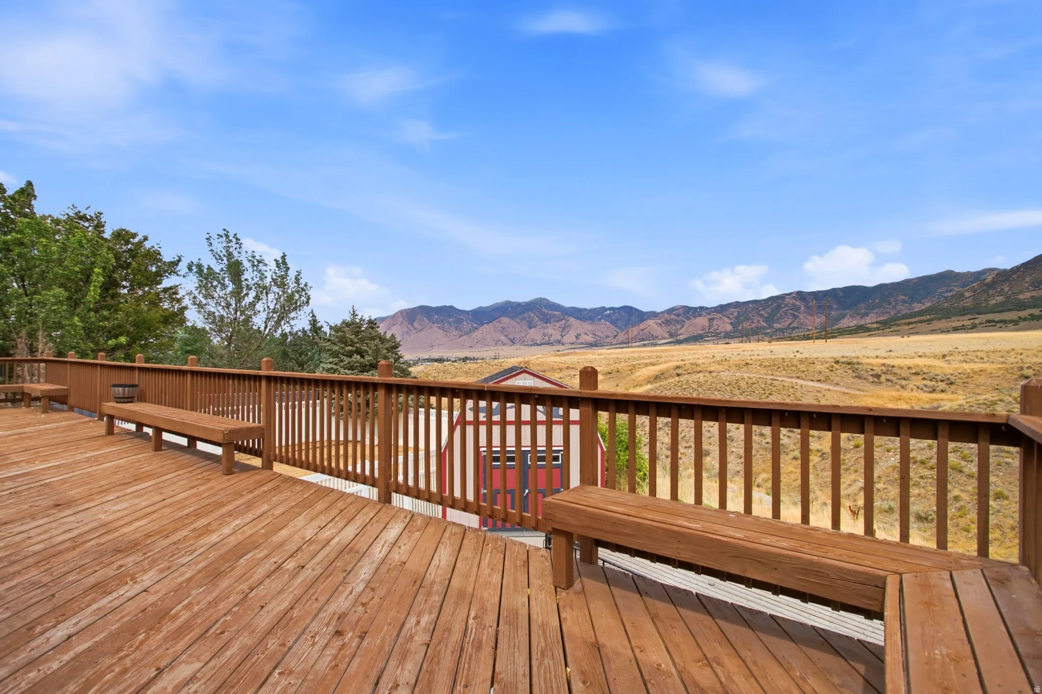 Expansive wood-finish deck featuring integrated benches and a wood railing