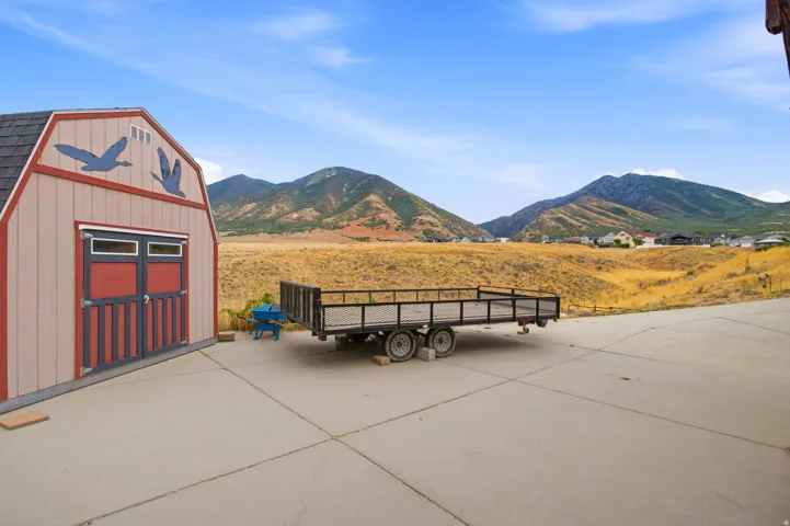 Spacious concrete pad with a barn-style shed featuring red doors and a shingled roof