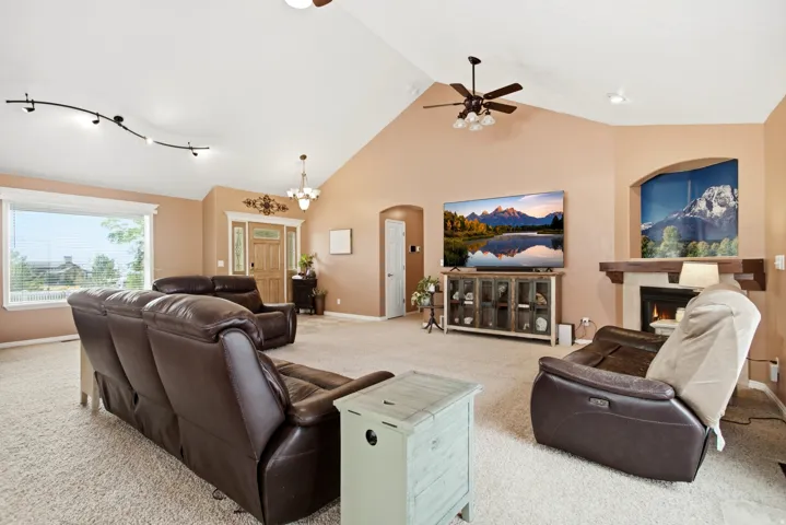 Vaulted ceilings create an expansive feel in this living area, featuring a built-in fireplace with a stone surround and wood mantel