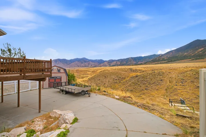 Expansive concrete patio with a wooden deck overhead, providing an outdoor living area