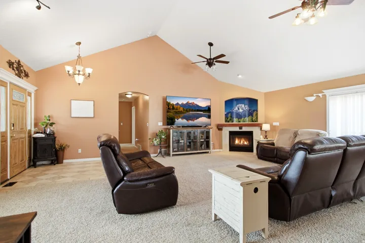 Spacious living area featuring vaulted ceilings, a built-in fireplace with a wood mantle, and wall-to-wall carpeting