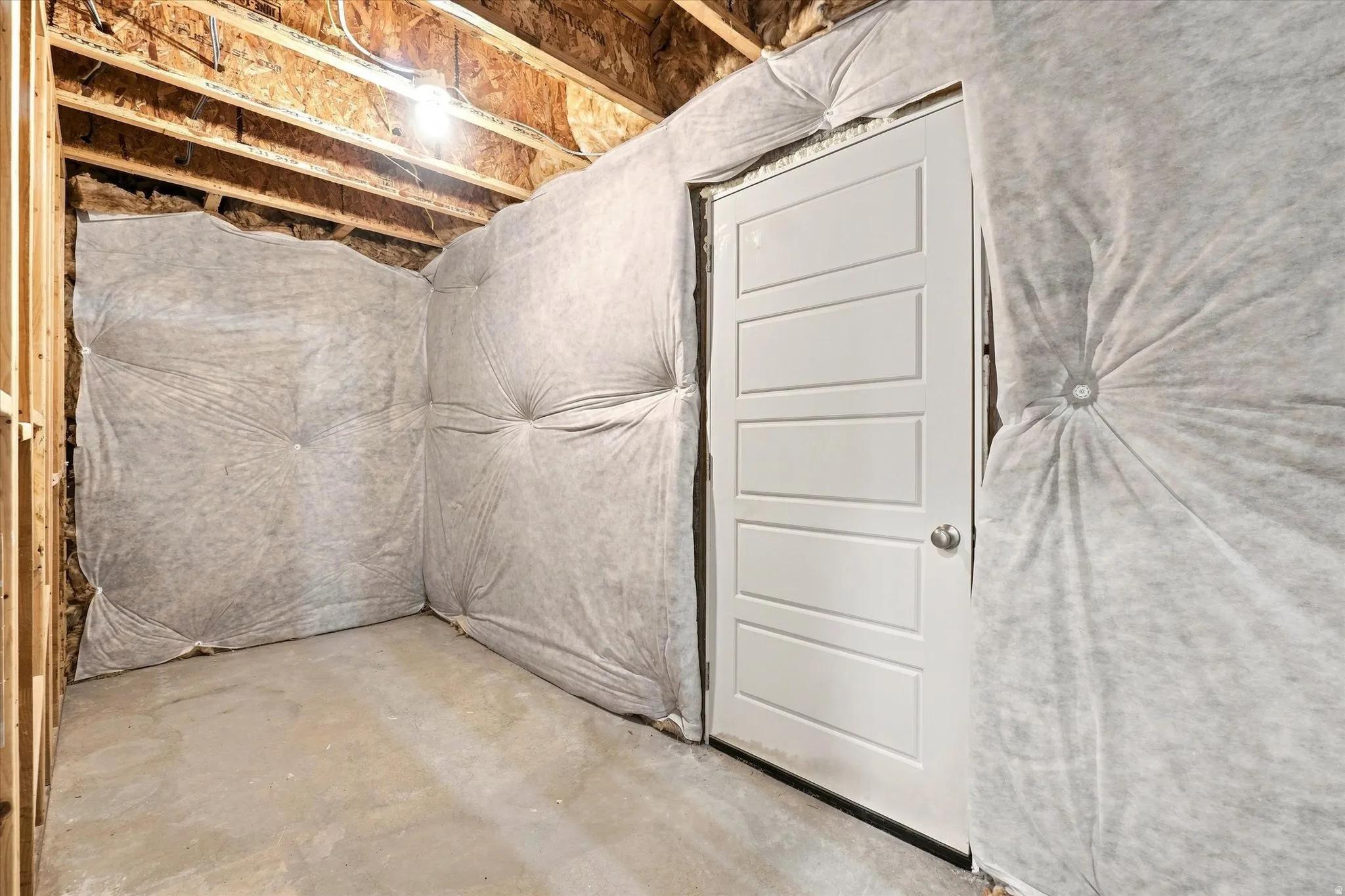 Unfinished interior space featuring exposed wood framing, batt insulation, and a concrete floor