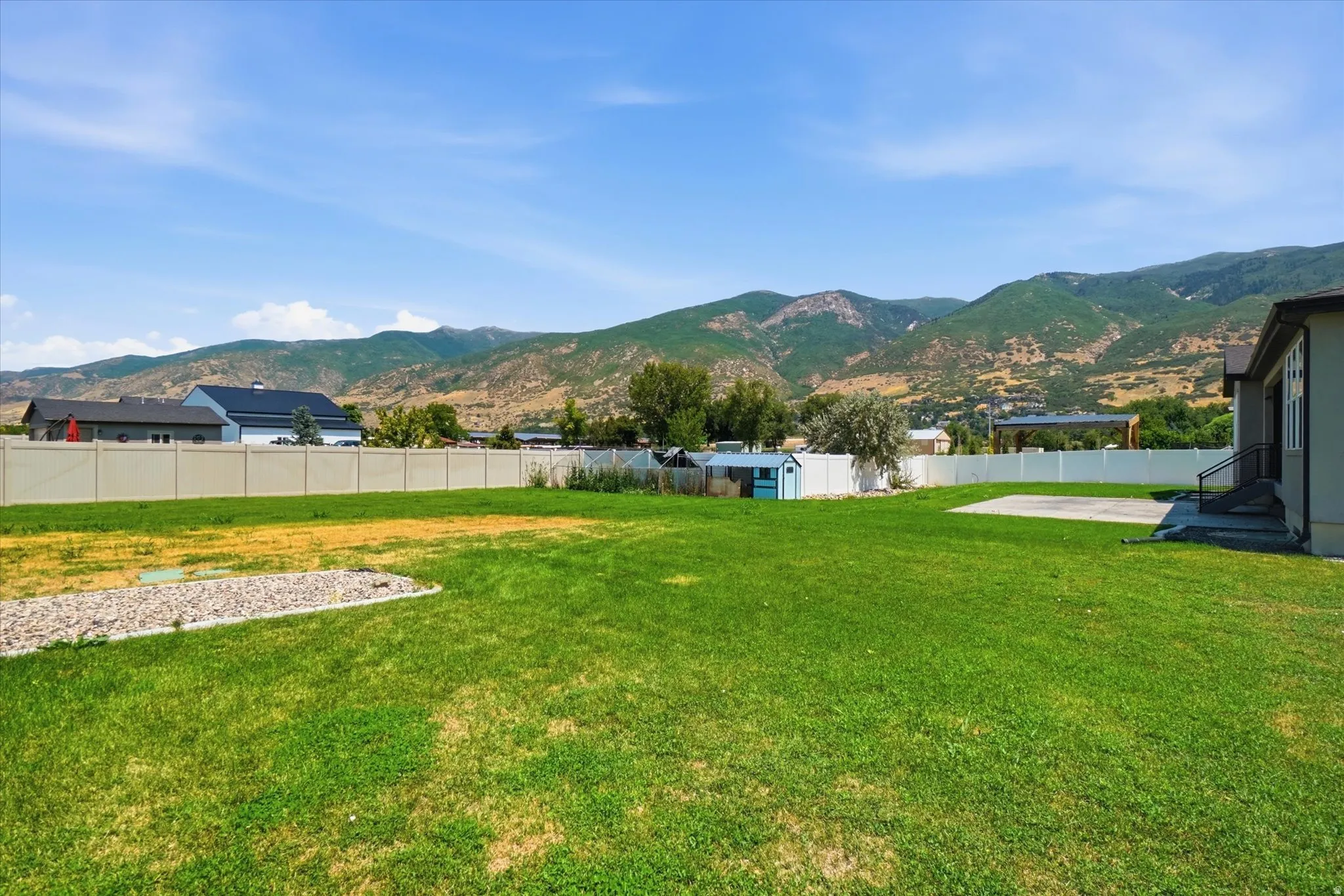 Spacious green lawn with a white privacy fence and a rear concrete patio
