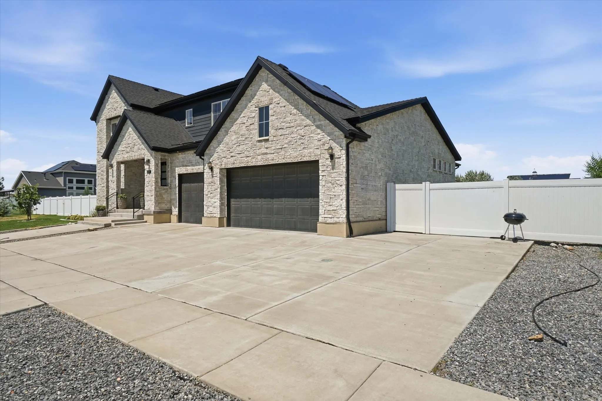 Modern stone-clad exterior featuring a two-car garage with dark paneled doors