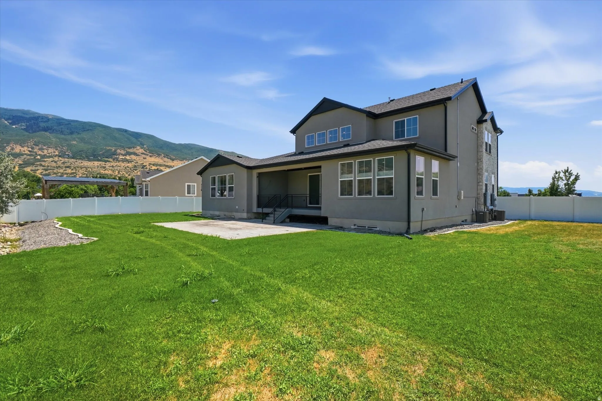 Spacious backyard featuring a large concrete patio, a covered patio area, and a white vinyl privacy fence