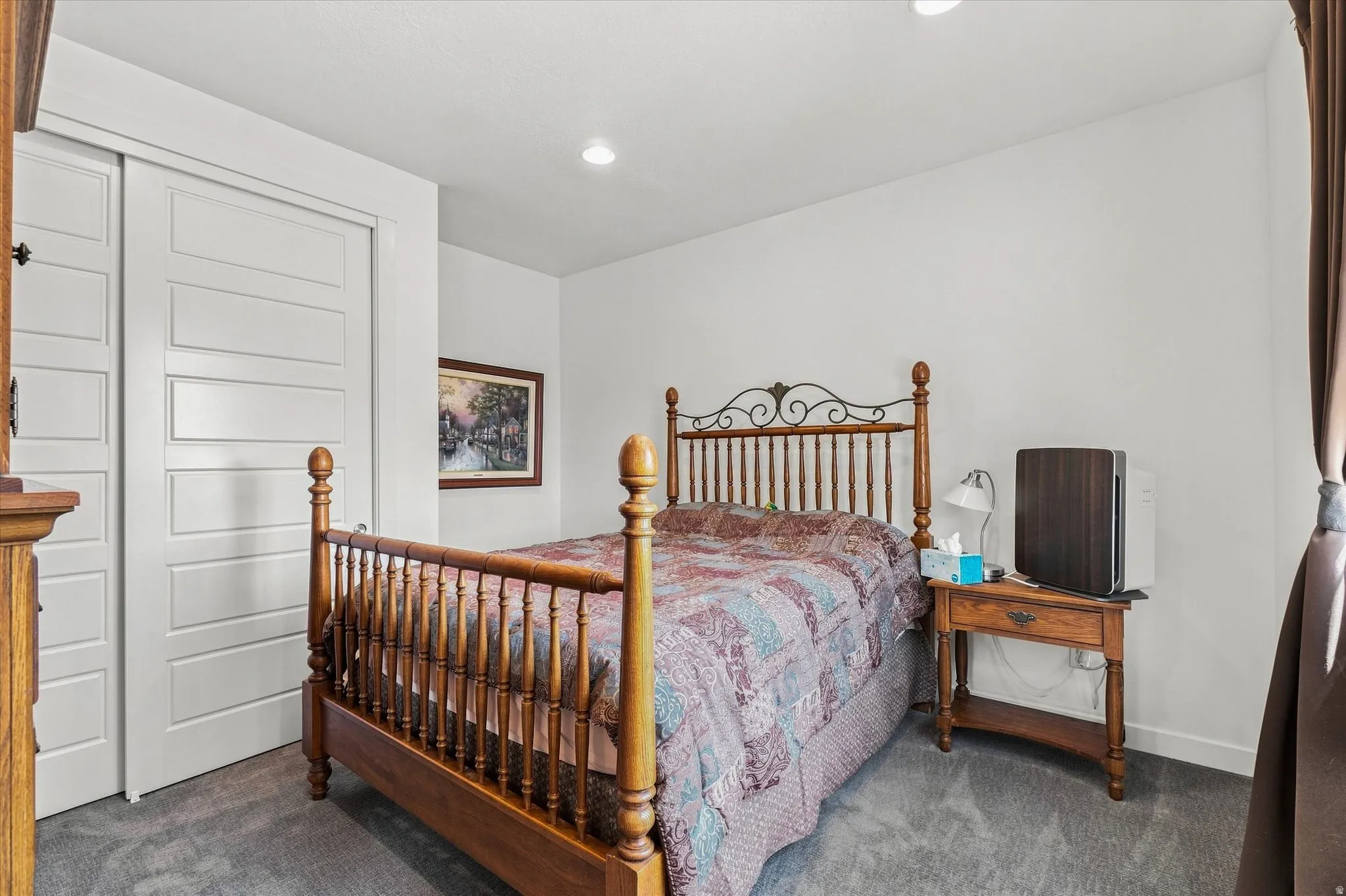 Recessed lighting illuminates this room, featuring light gray carpeting and white walls