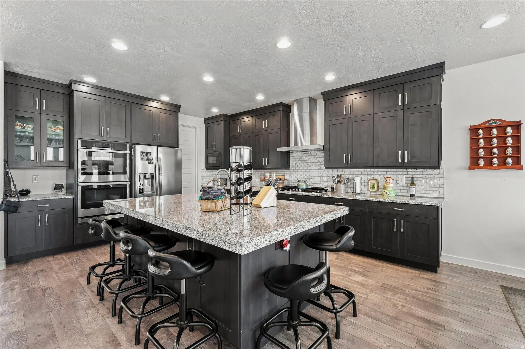 Spacious kitchen featuring dark wood cabinetry, a large center island with a light-toned countertop, stainless steel appliances, and wood-finish flooring