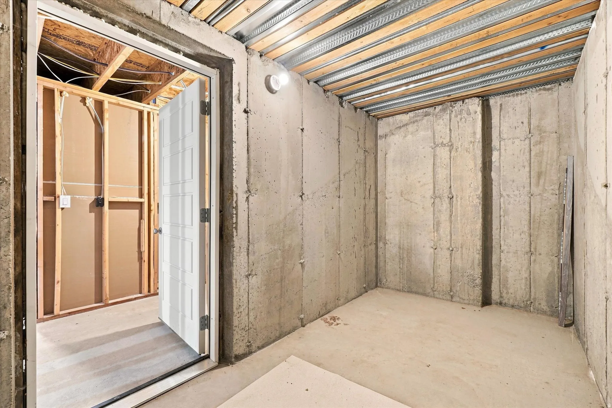 Unfinished basement space featuring exposed concrete walls and ceiling joists