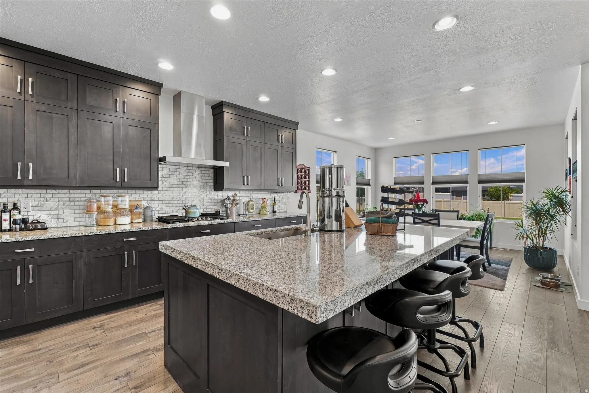 Expansive kitchen featuring a large island with seating, dark wood-finish cabinetry, granite countertops, and a white subway tile backsplash
