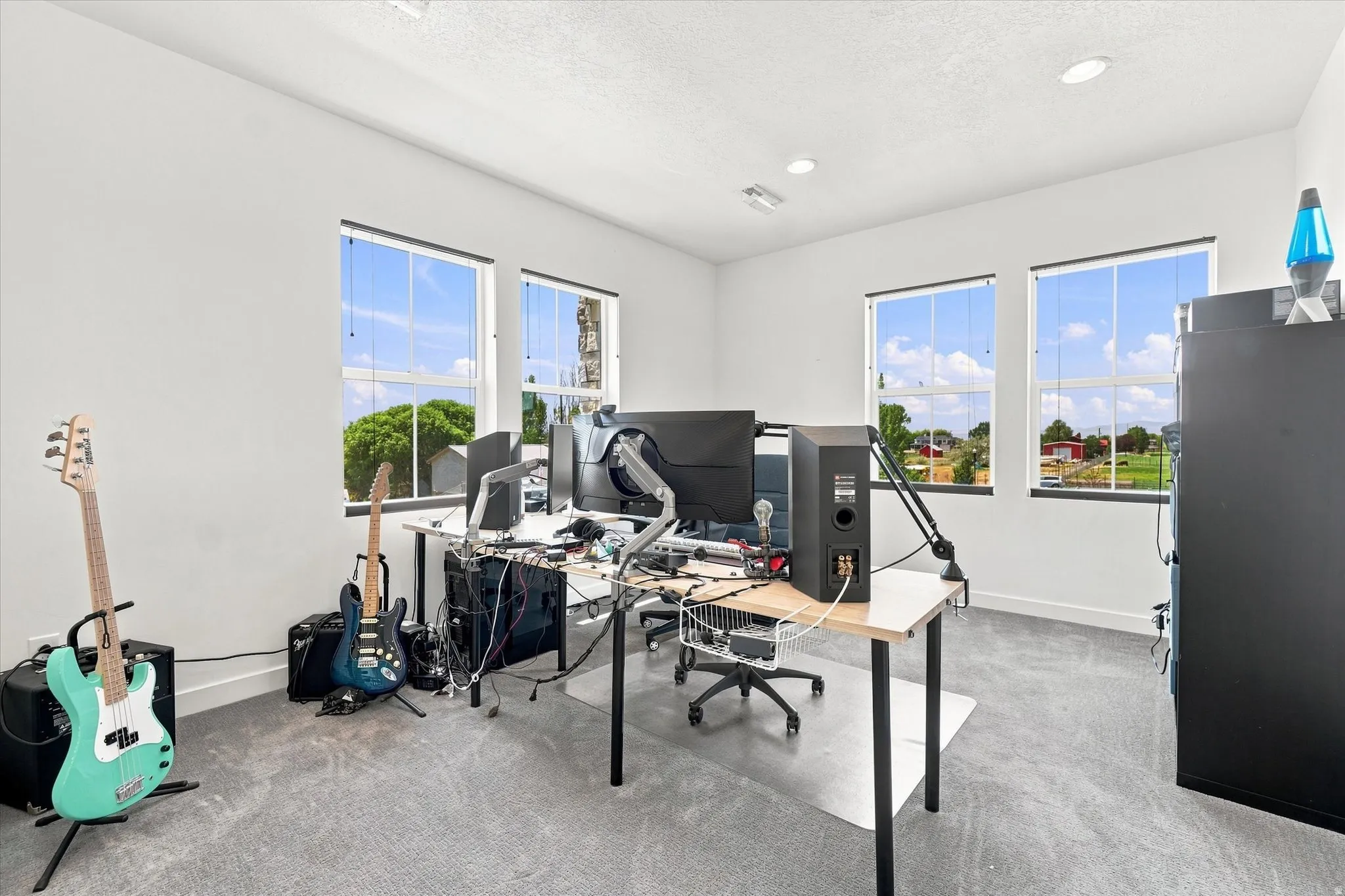 Light-filled room featuring five windows, neutral white walls, and gray carpet flooring