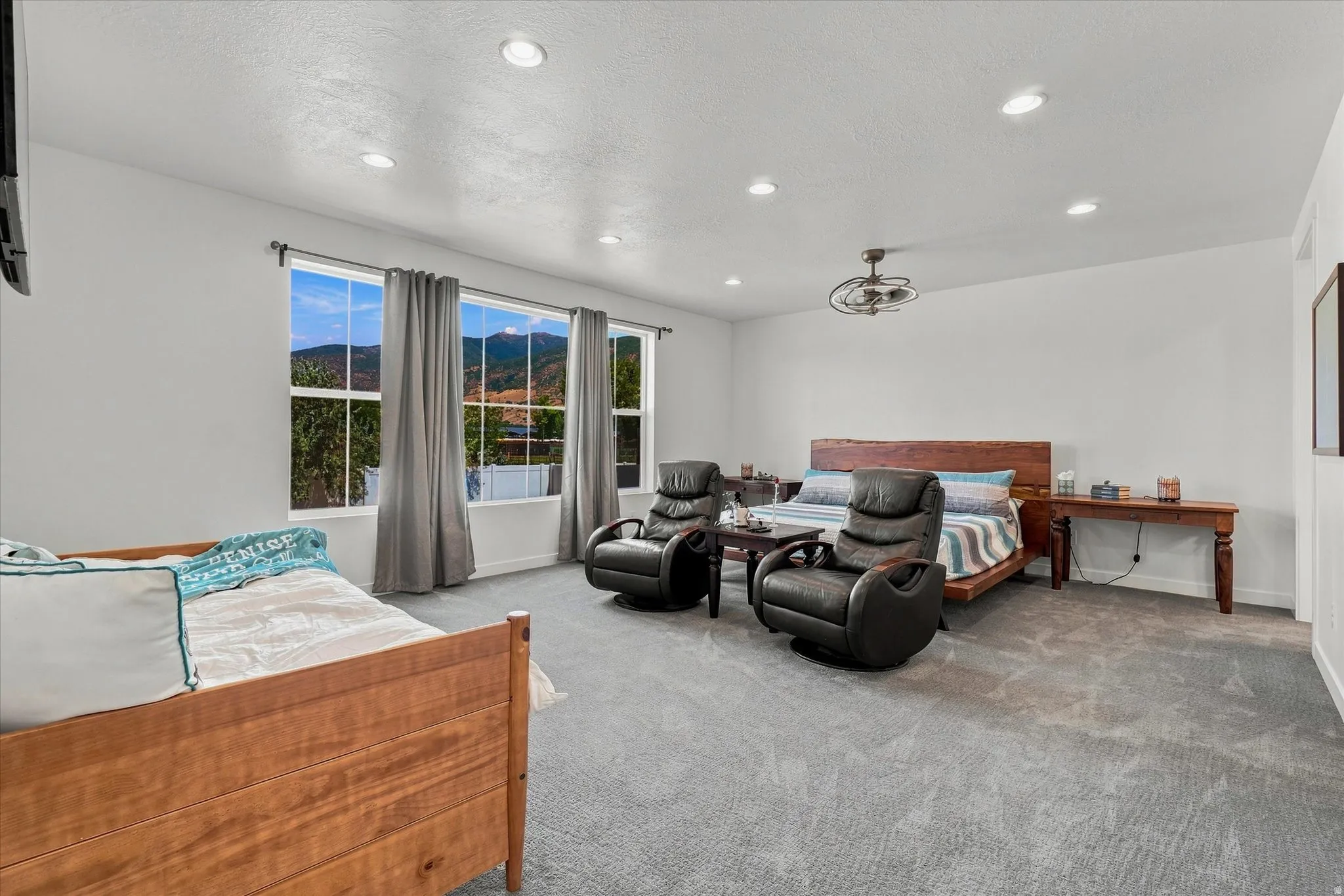 Spacious room featuring neutral carpeting, multiple windows with mountain scenery, recessed lighting, and a ceiling fan