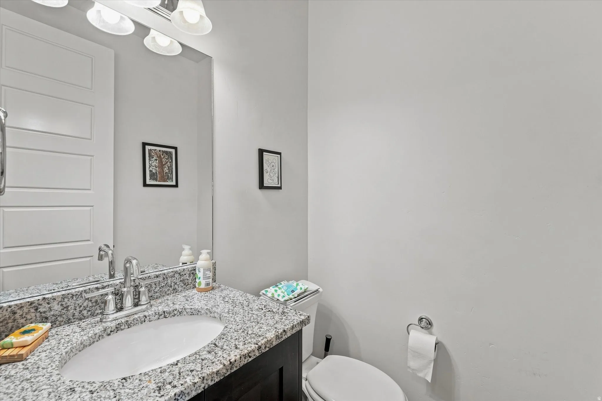 Bathroom featuring a granite countertop with an undermount sink, dark wood-finish vanity, and a large wall mirror