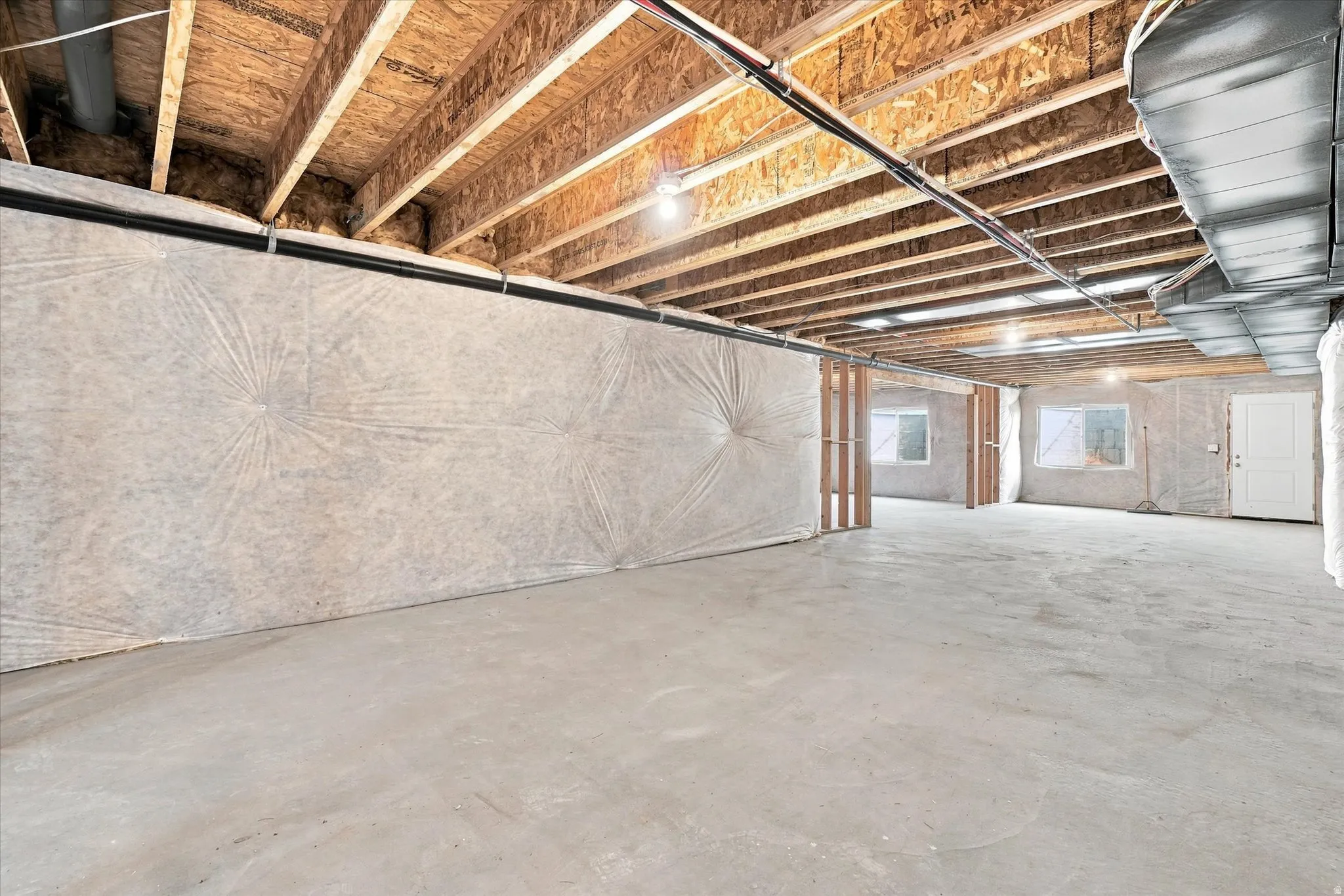 Unfinished basement with exposed ceiling joists and concrete flooring